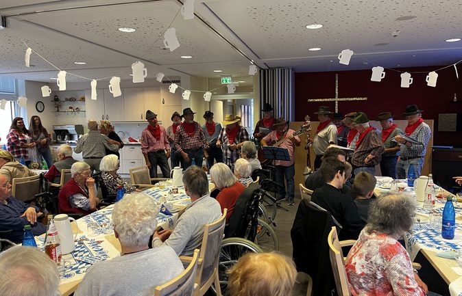 Seniorinnen und Senioren beim Herbstfest mit singender Männergruppe und Bierkrug-Girlande